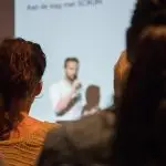 Speaker in front of room making a presentation to audience.